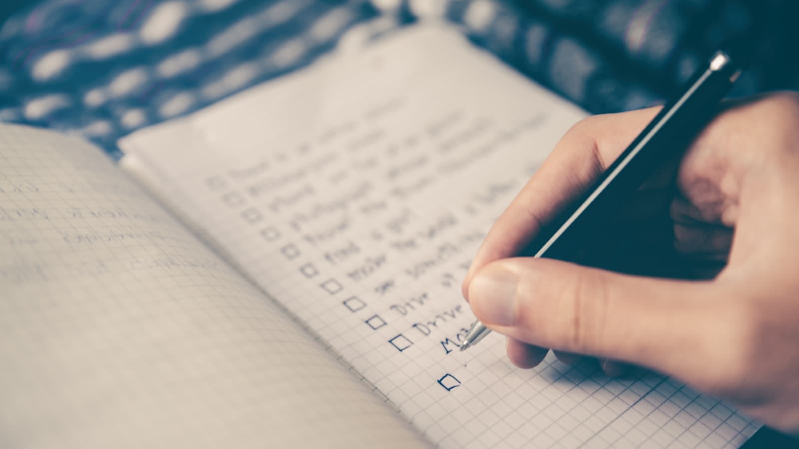 Mano tildando ítems de un checklist escrito a mano en un cuaderno
