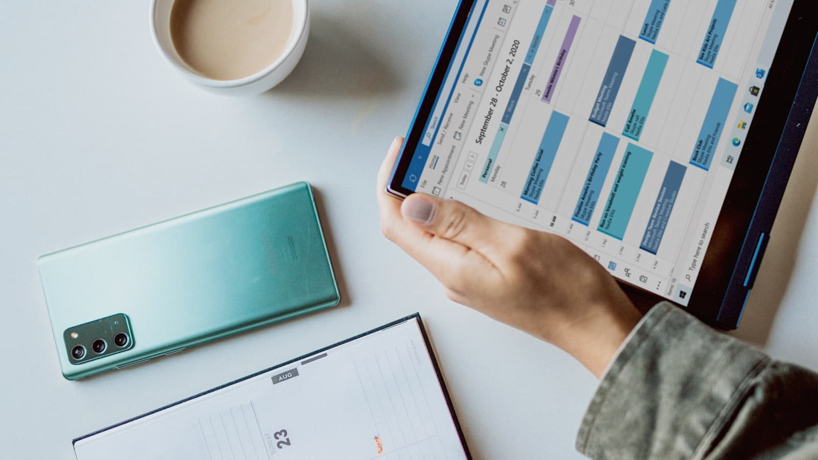 Escritorio con una agenda en pantalla, un celular y un cuaderno de planificación