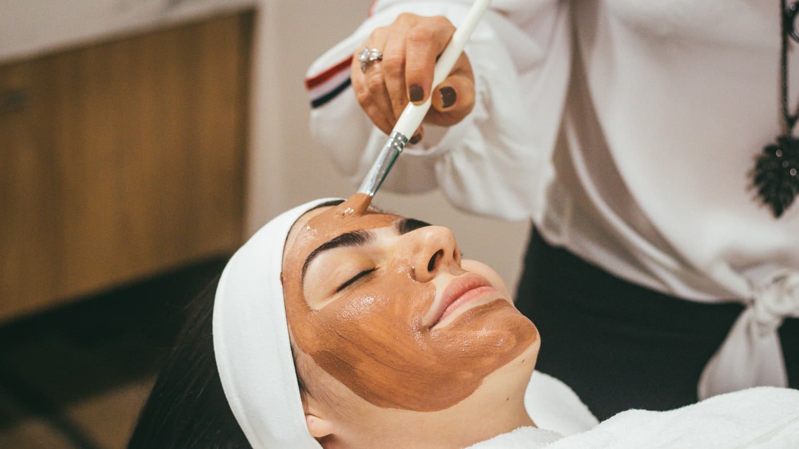 Profesional aplicando una máscara facial a una clienta en un centro de estética